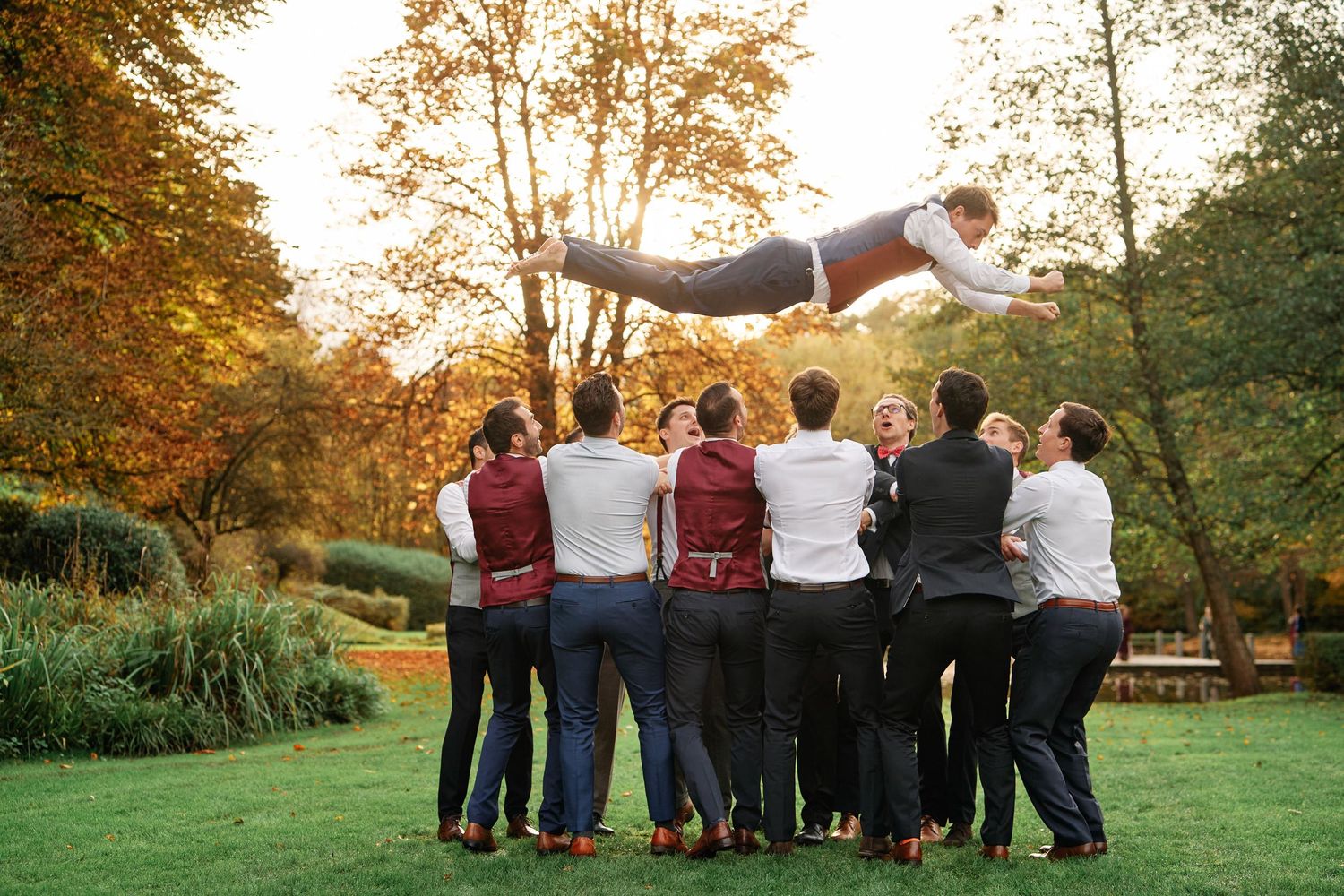 Group of friends standing together in a park during golden hour sunset with arms around each other.