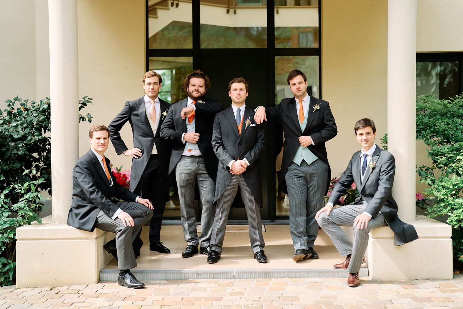 A group of formally dressed people sitting on stone steps showing their dress shoes and socks in a coordinated photo.