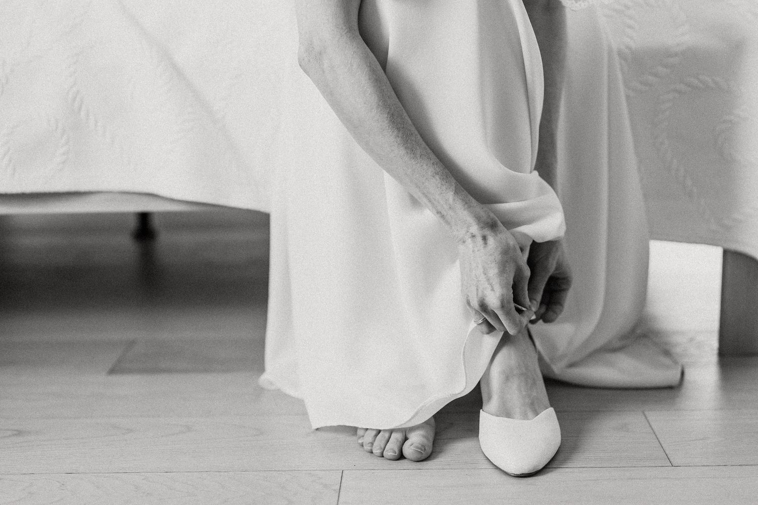 A row of wedding dress details showing the hem, shoes, and bare feet against a white background.