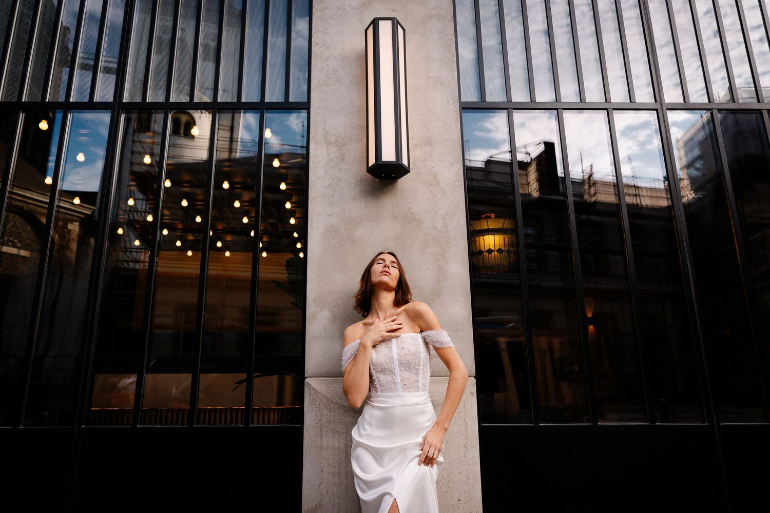 Elegant wedding venue interior with dramatic sloped glass ceiling and modern lighting fixtures.
