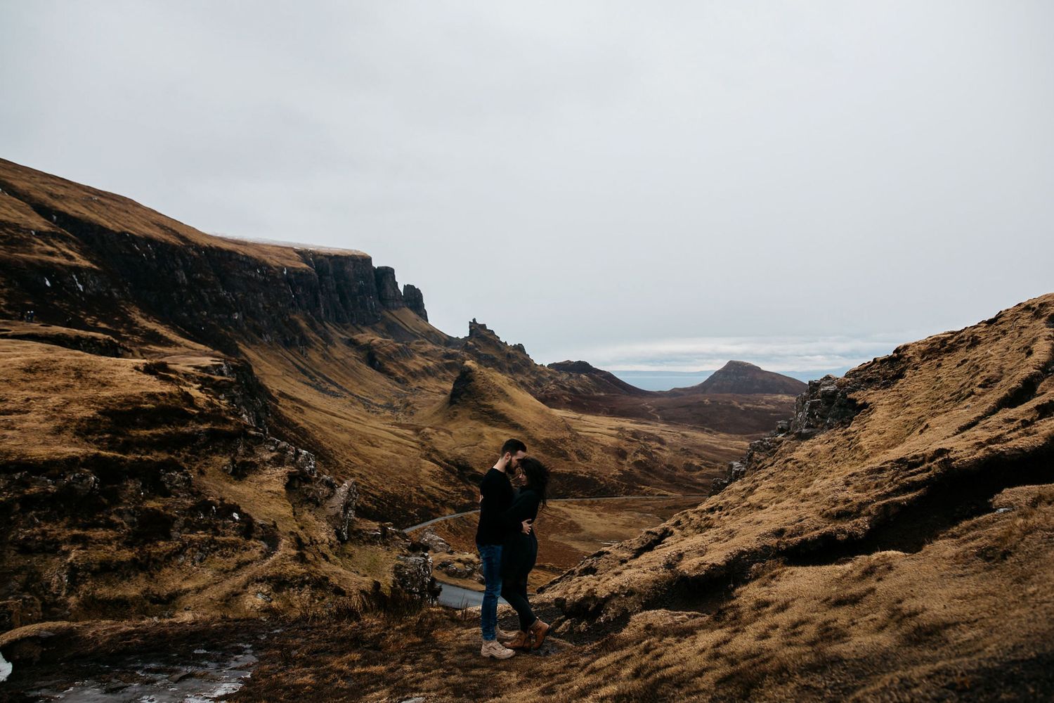 A lone hiker stands in the rugged landscape of Scotland's Quiraing on the Isle of Skye under moody skies.