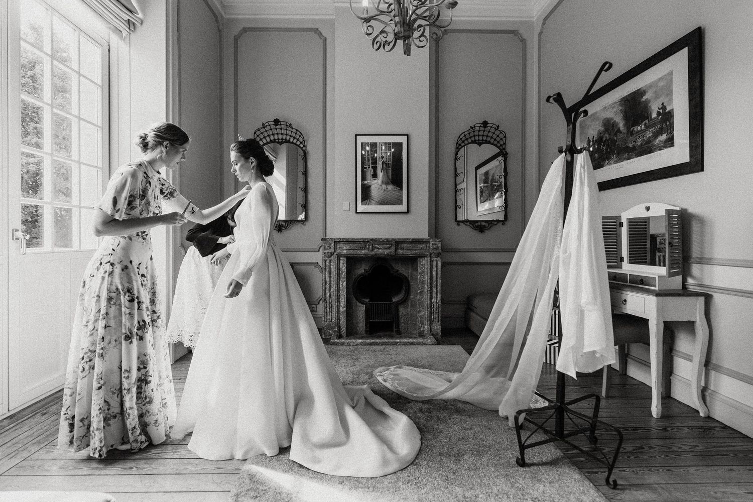 A series of black and white photographs showing wedding dresses displayed in an elegant room with vintage decor and framed art.