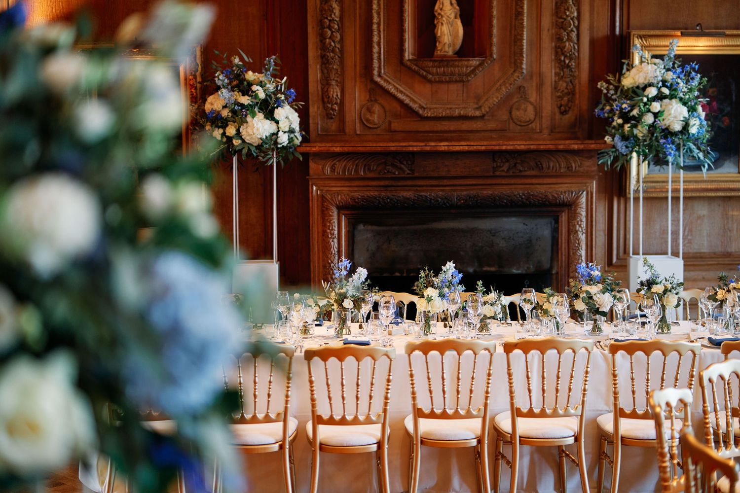Elegant wedding reception venue with wooden paneled walls and rows of white chiavari chairs set for celebration.