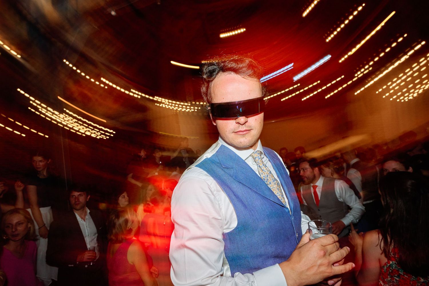 Guests dancing and celebrating at a lively wedding reception with warm lighting and festive decorations.