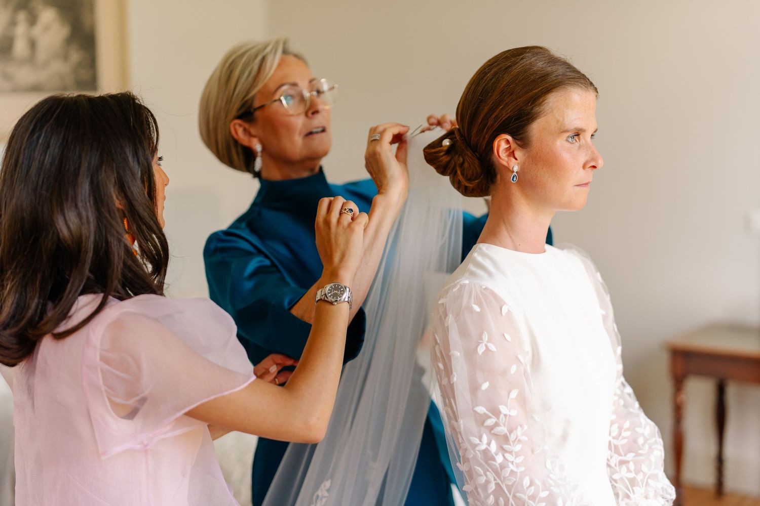 Wedding party getting ready together in a bright room with makeup and styling preparations underway.