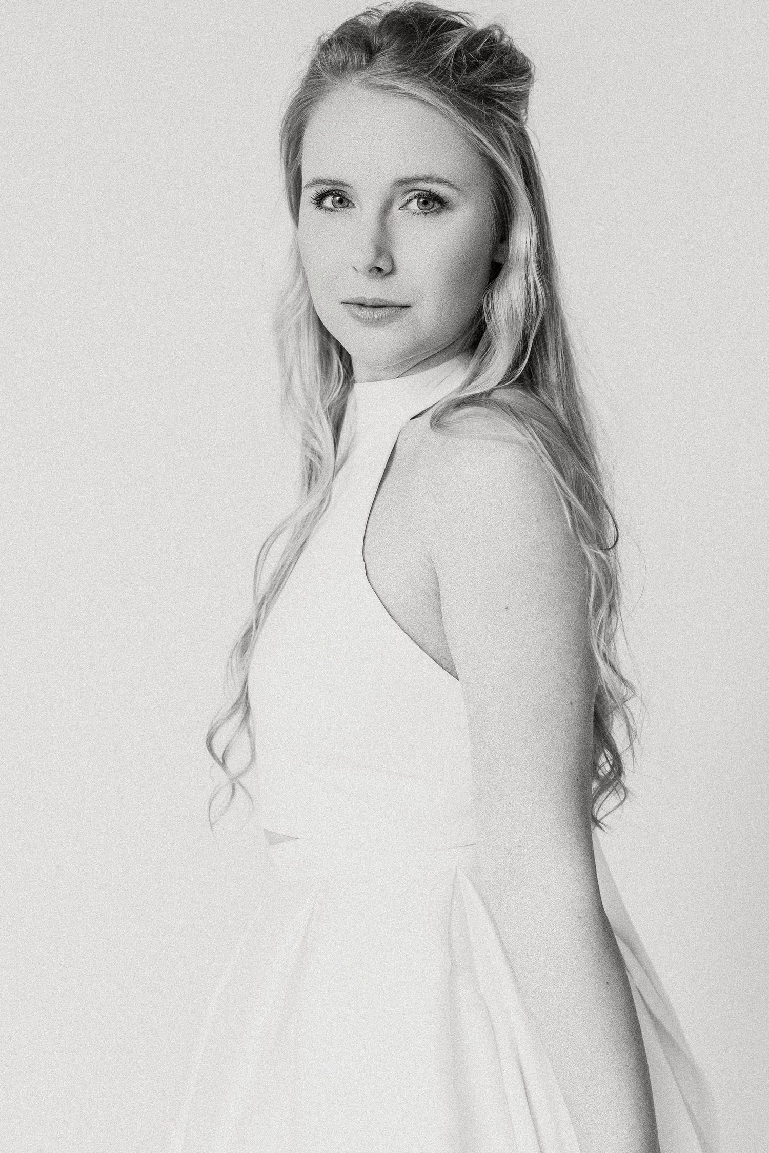 Black and white portrait series showing a person with long blonde hair in a white dress posing against a light background.