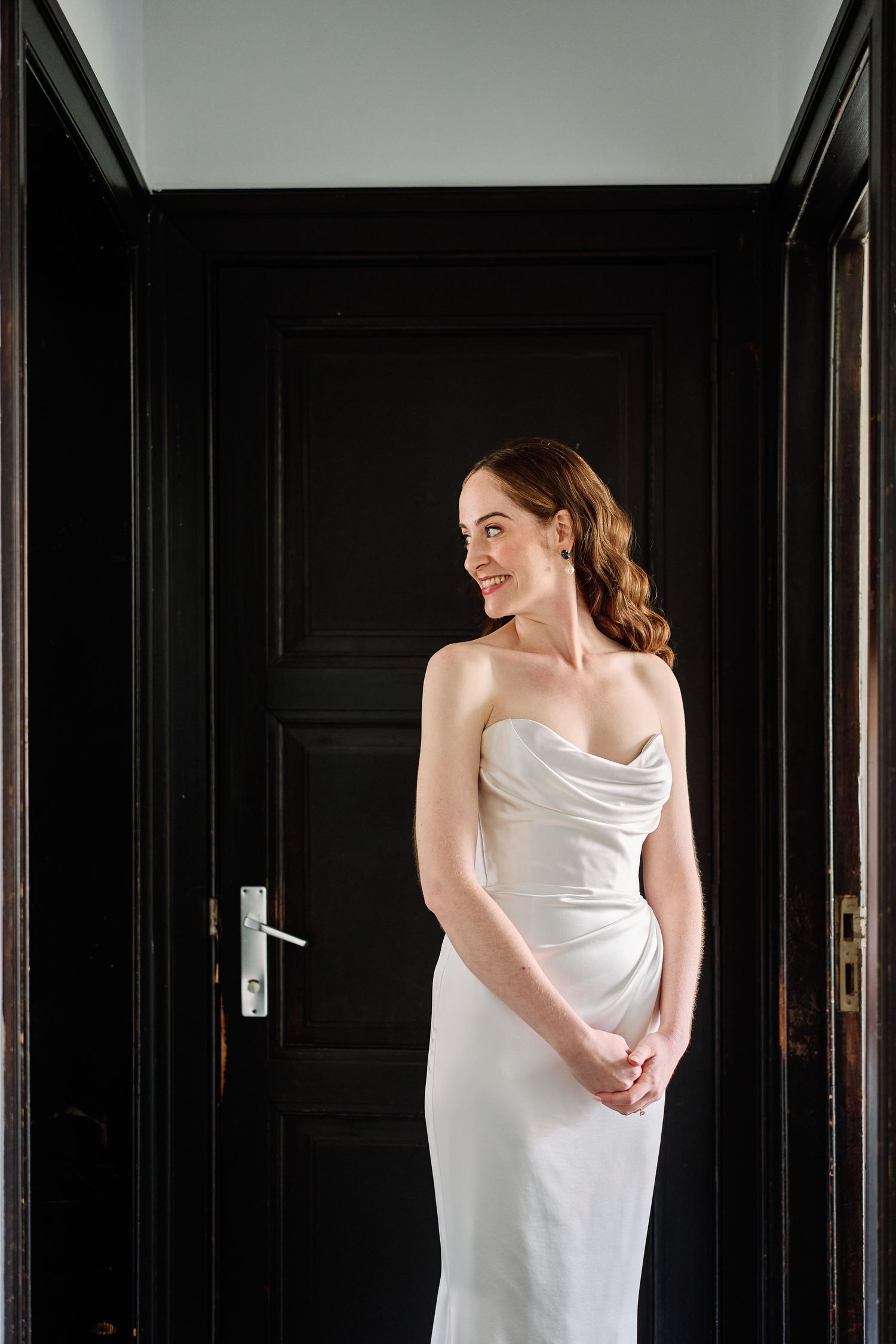 A figure wrapped in white fabric poses against dark walls in a triptych-style composition.