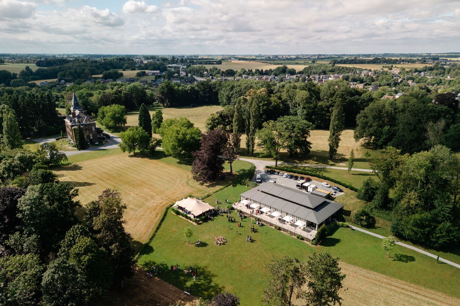 Aerial view of a modern estate house with manicured grounds surrounded by rolling countryside and woodlands.