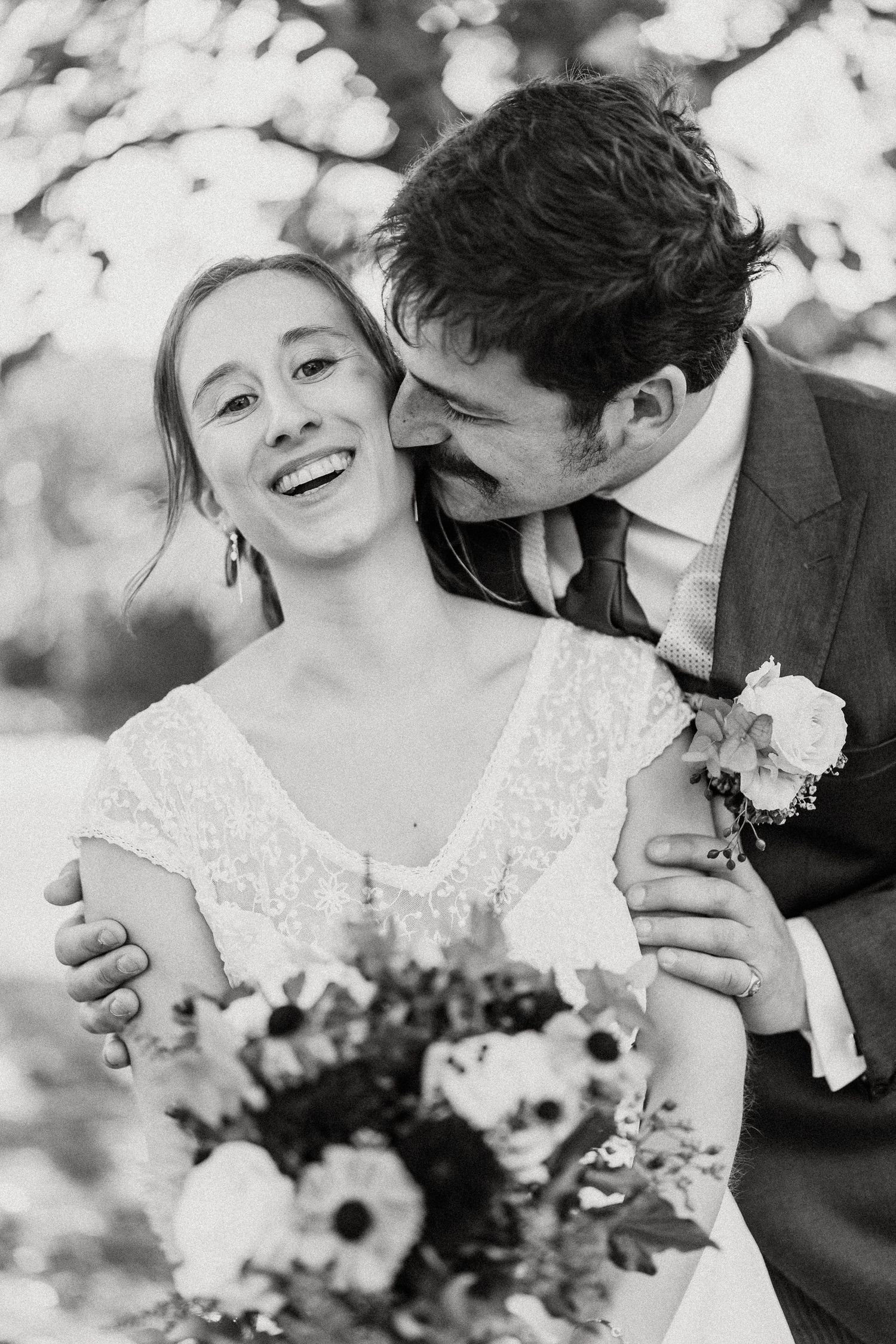 A romantic black and white wedding photo series showing tender moments between newlyweds with a floral bouquet.