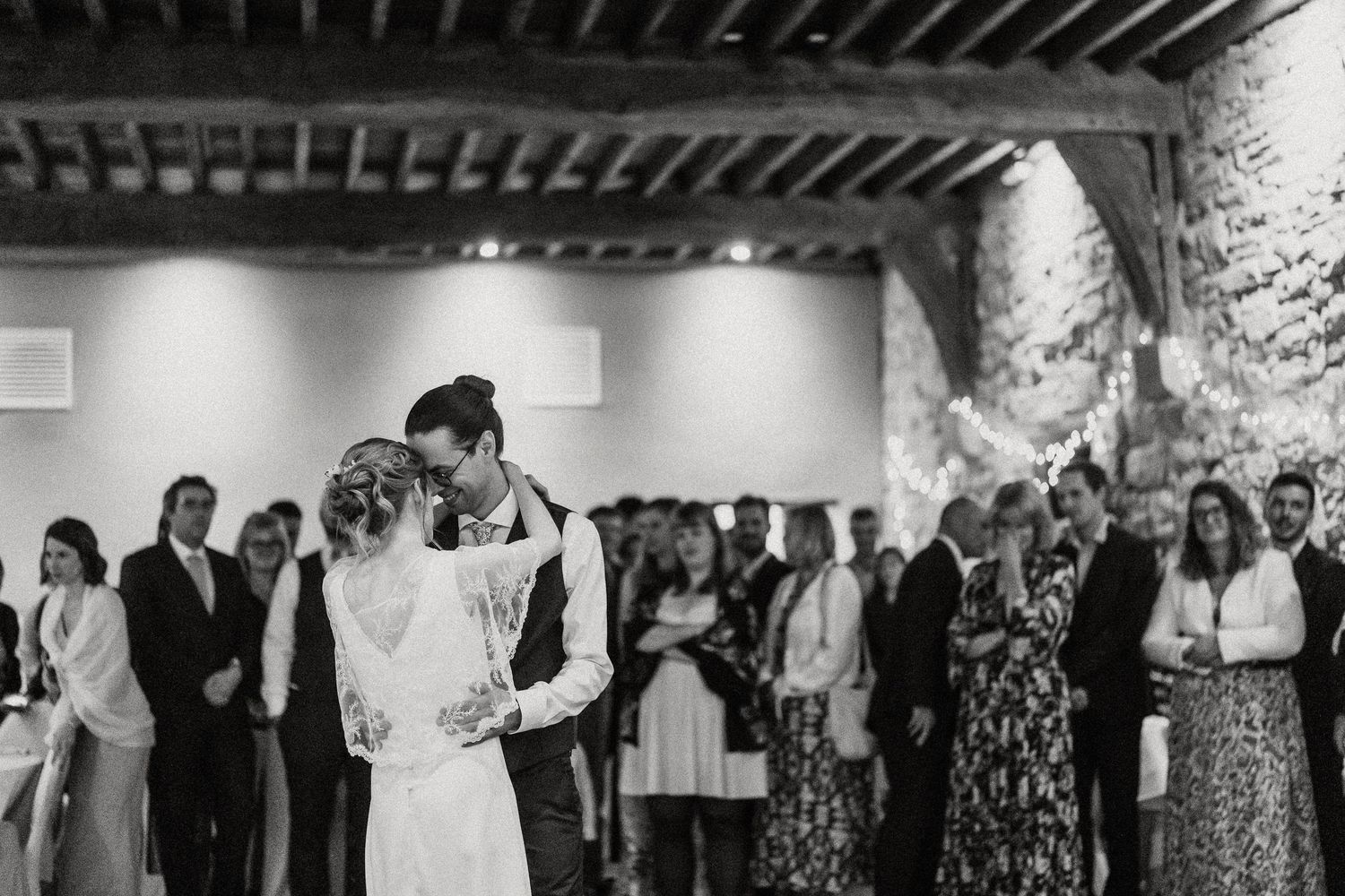 Wedding guests dance and celebrate together on a dark wooden floor during an indoor reception party.