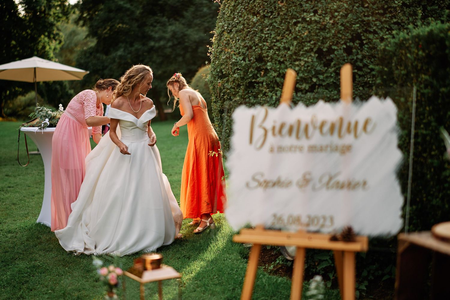 Rustic wooden wedding signs and decorations displayed on an outdoor lawn during a summer celebration.