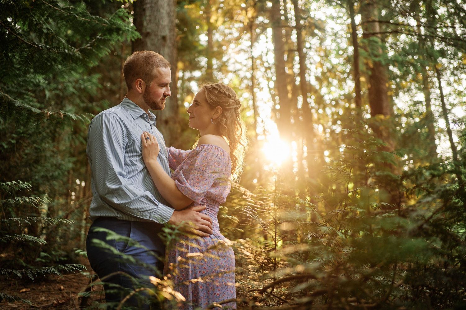 A couple shares an intimate moment in a sunlit forest during a romantic golden hour photoshoot.