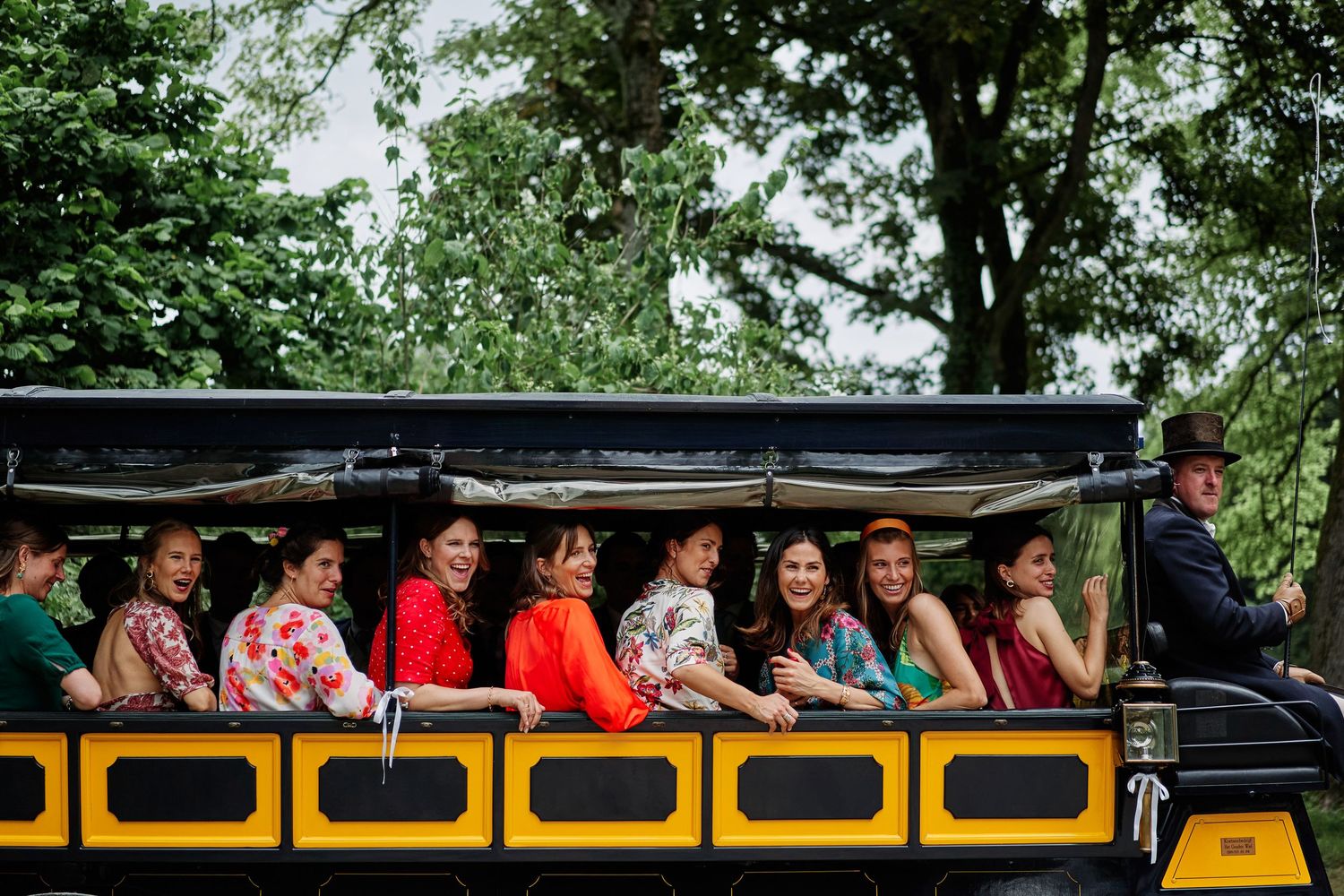 Students sit together on a yellow school bus during a field trip through lush green surroundings.