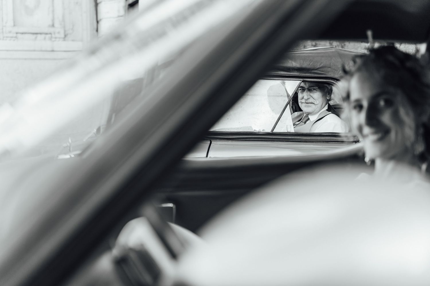 Black and white photo taken through a car window showing someone in a cowboy hat in another vehicle.