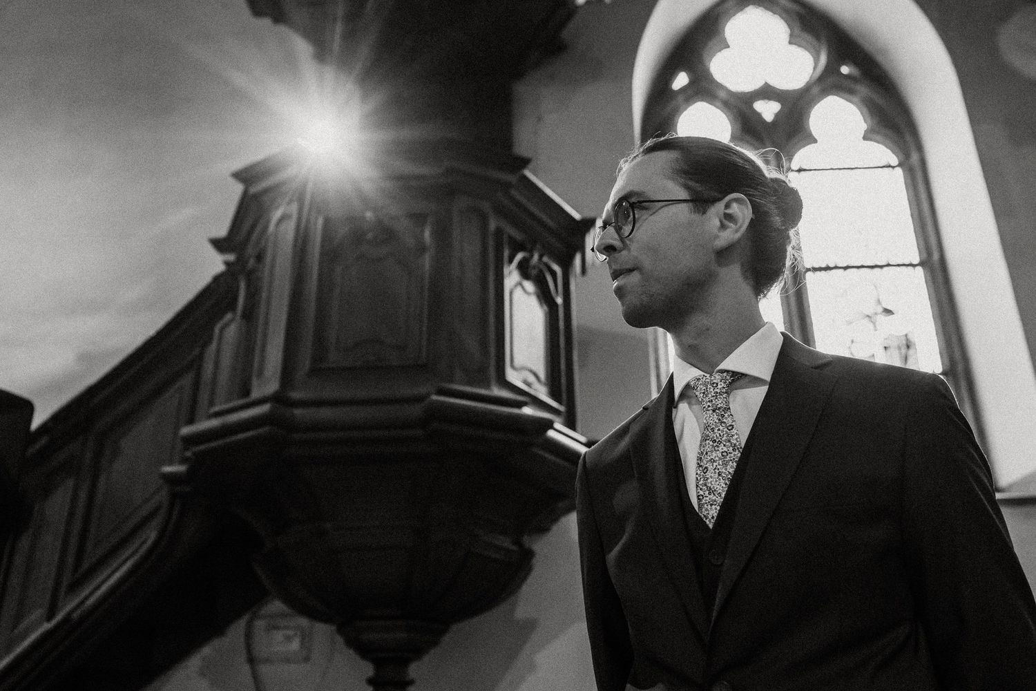 Black and white photo series showing a dramatic wedding scene with lens flare and silhouettes in a church setting.