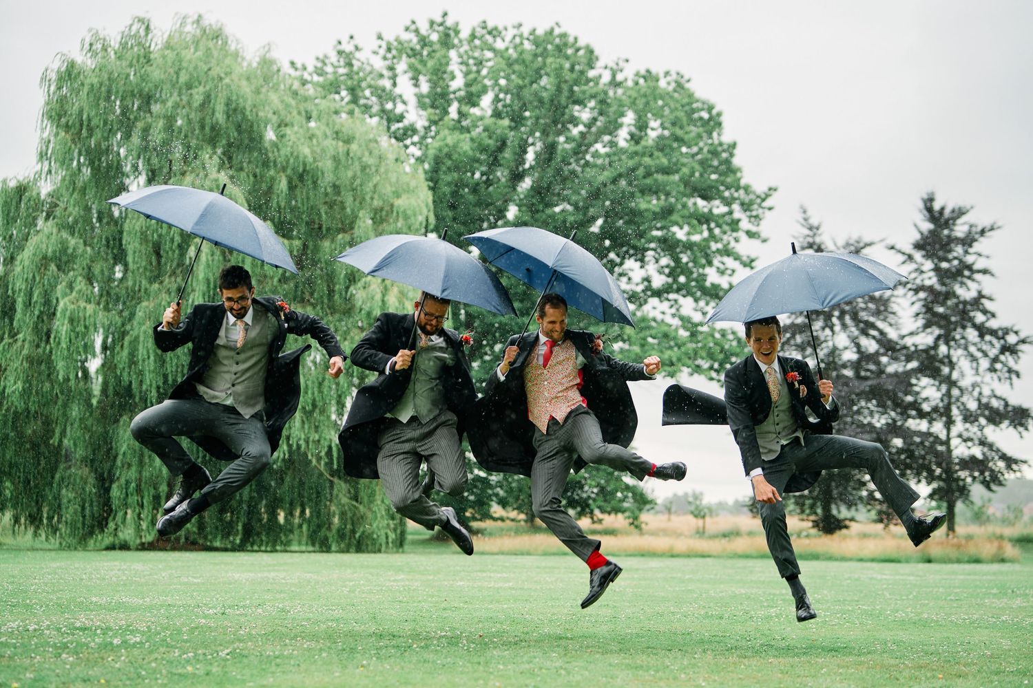 A sequence of dancers performing synchronized umbrella choreography in a grassy field on an overcast day.
