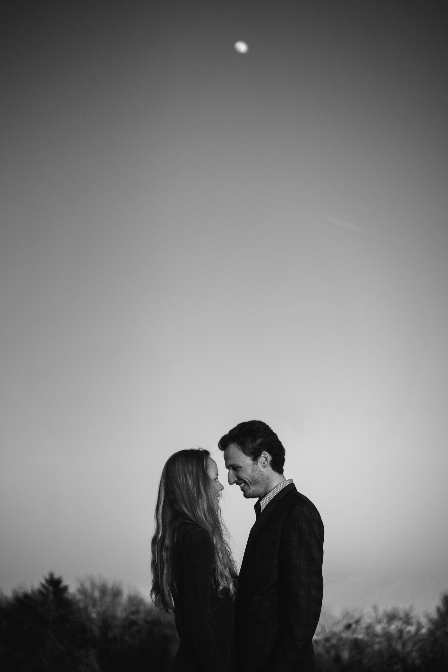 Romantic black and white silhouettes of a couple sharing intimate moments against a moody sky background.
