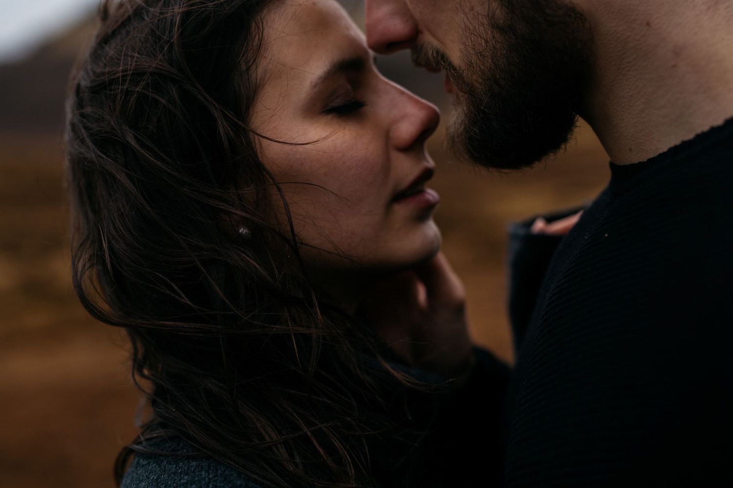 A romantic couple in silhouette share intimate kisses against a warm brown background.