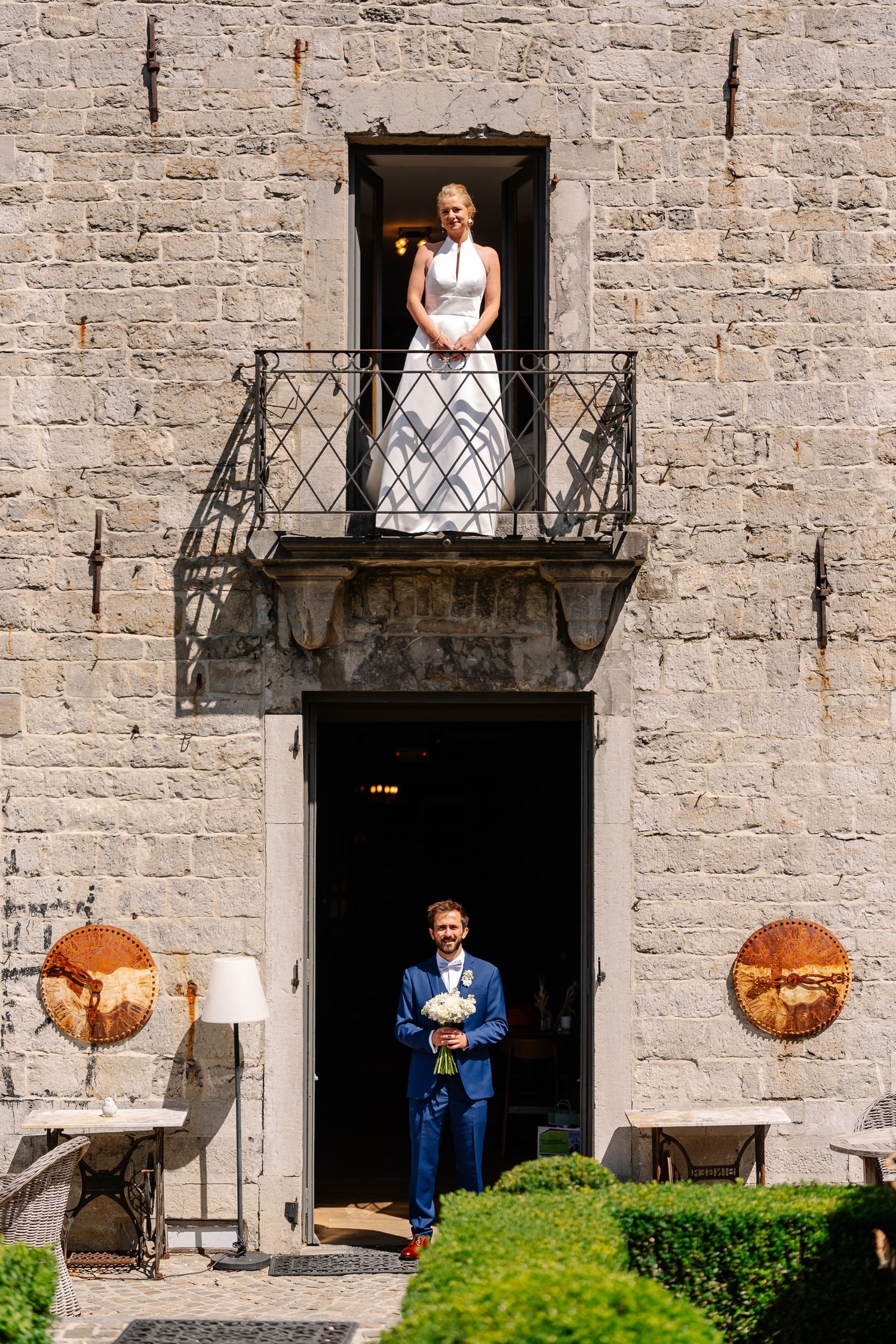 Stone castle wall with ornate balconies and doorways decorated with rustic lanterns and greenery.