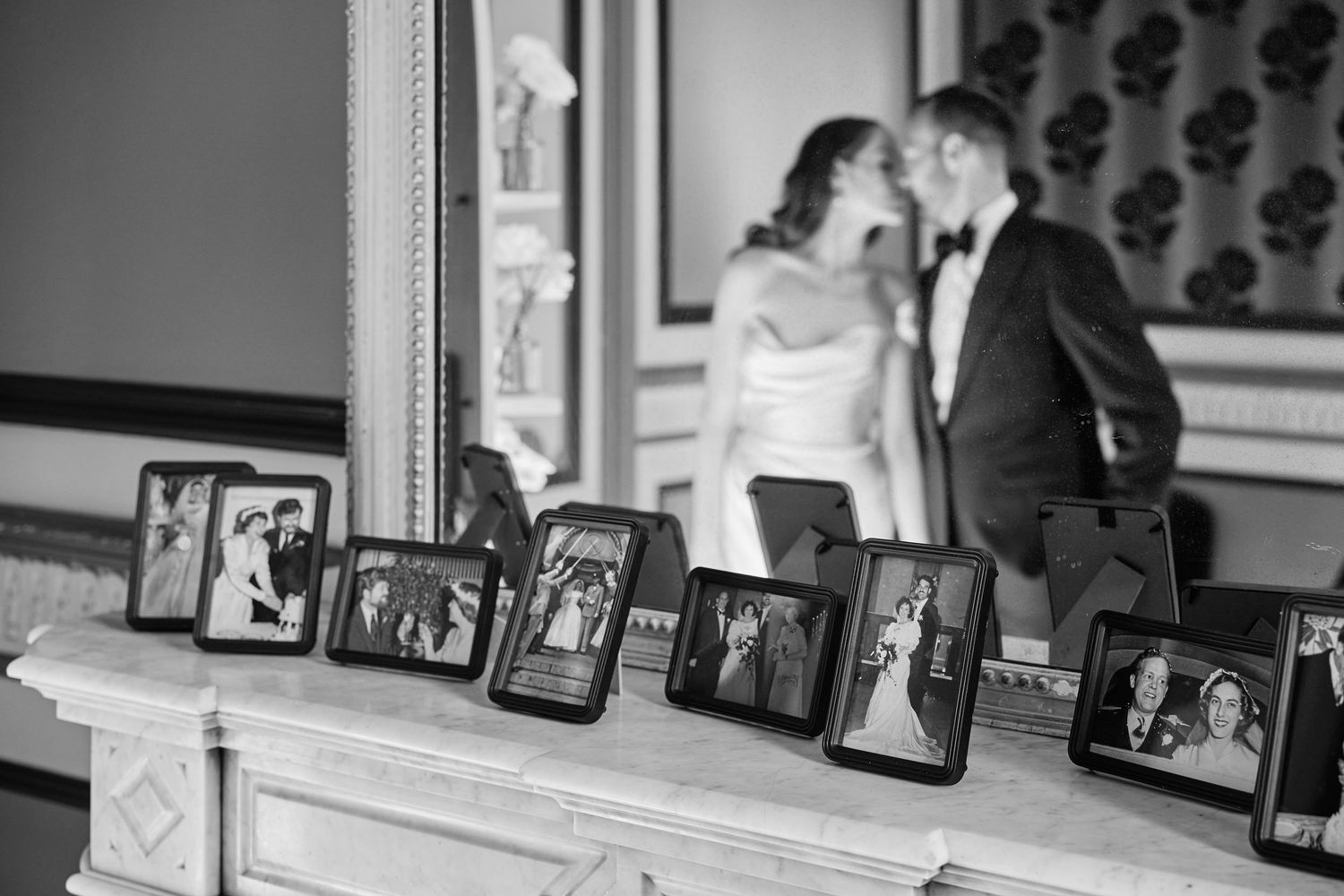 A collection of framed photographs arranged on a wooden shelf in black and white tones.