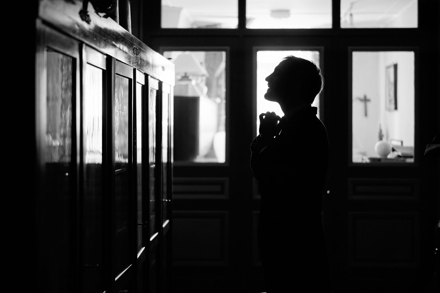 A dark hallway with multiple doorways and windows creating dramatic silhouettes and shadows.