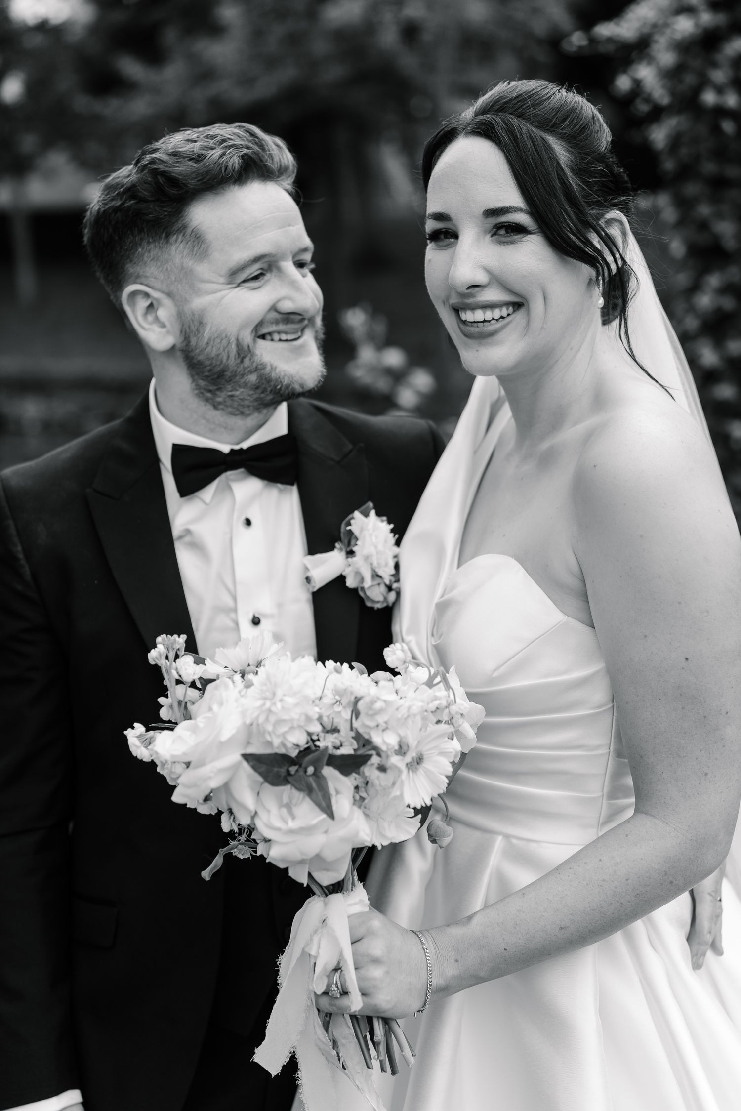 Black and white wedding photo series showing candid moments between newlyweds with white floral bouquet.