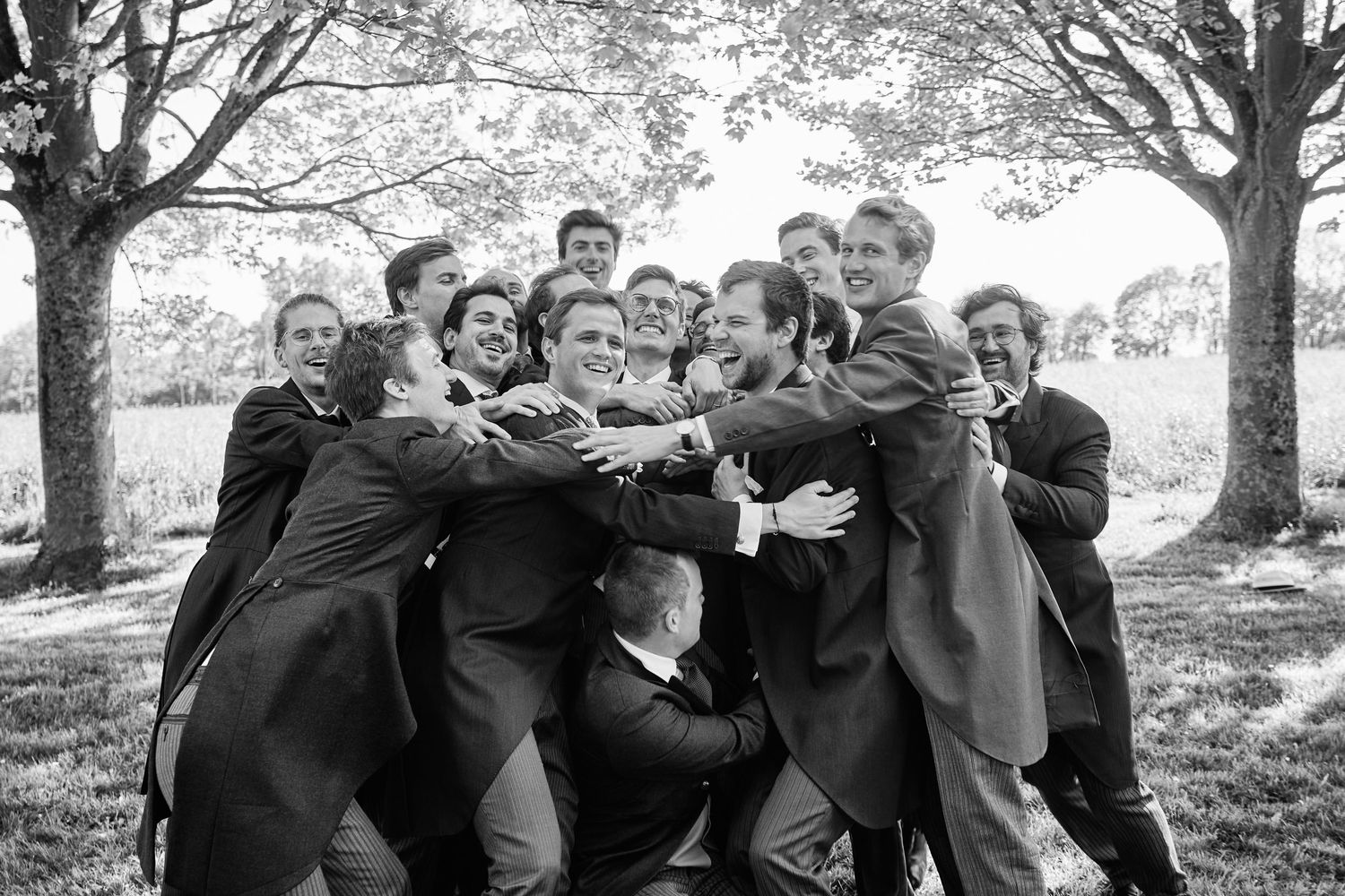 A group of people pose together outdoors in a black and white photo while leaning and smiling at the camera.