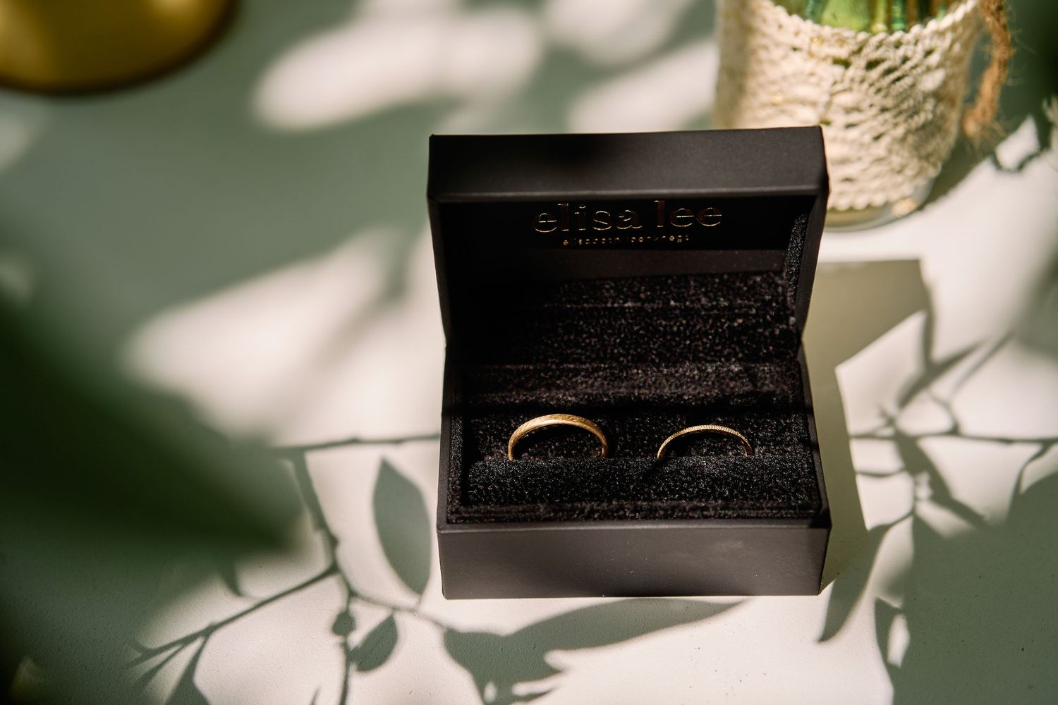 Wedding rings cast dramatic shadows on a textured surface in natural light.