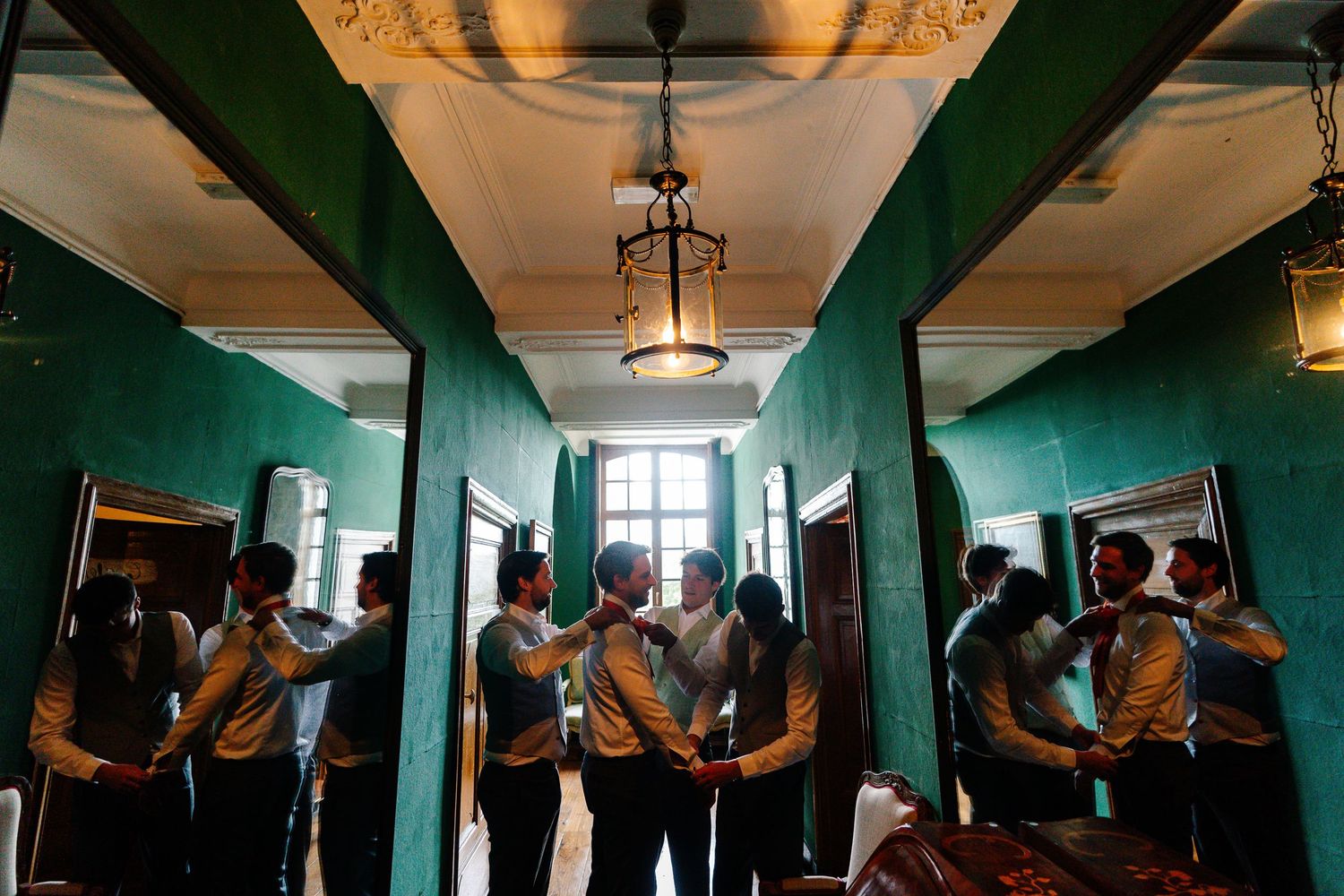 People gathered in a hallway with emerald green walls and ornate ceiling fixtures.