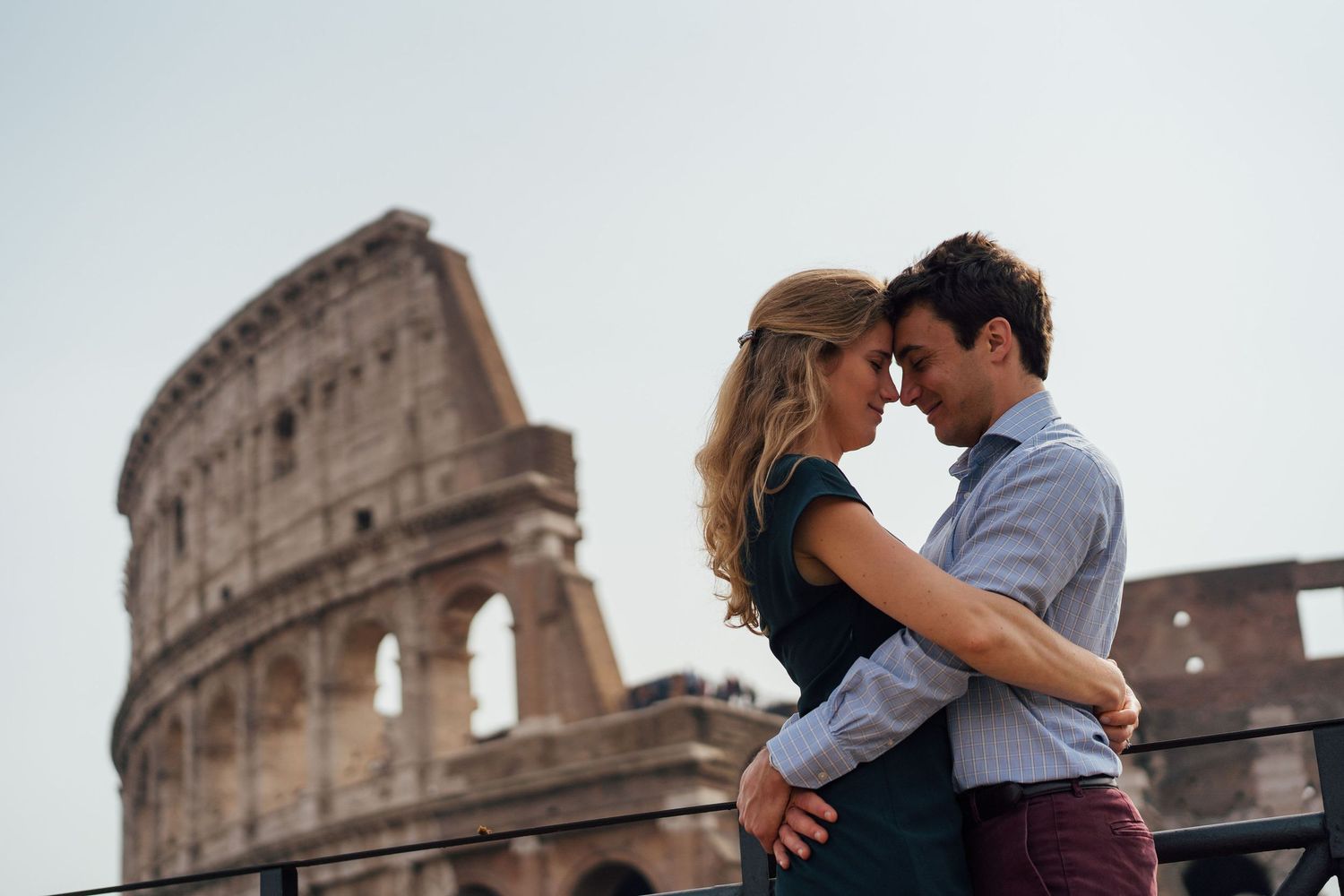 Romantic couple embraces near the historic Colosseum in Rome, Italy during sunset.