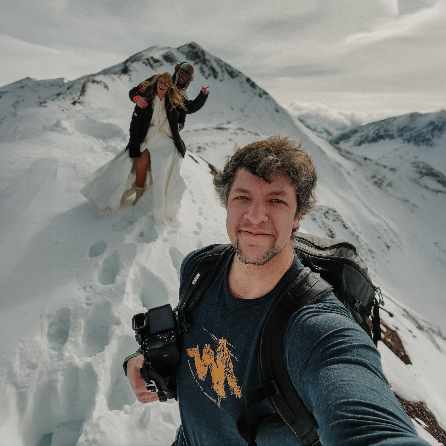 A person taking selfies while skiing in snowy mountains with cloudy skies and winter gear.