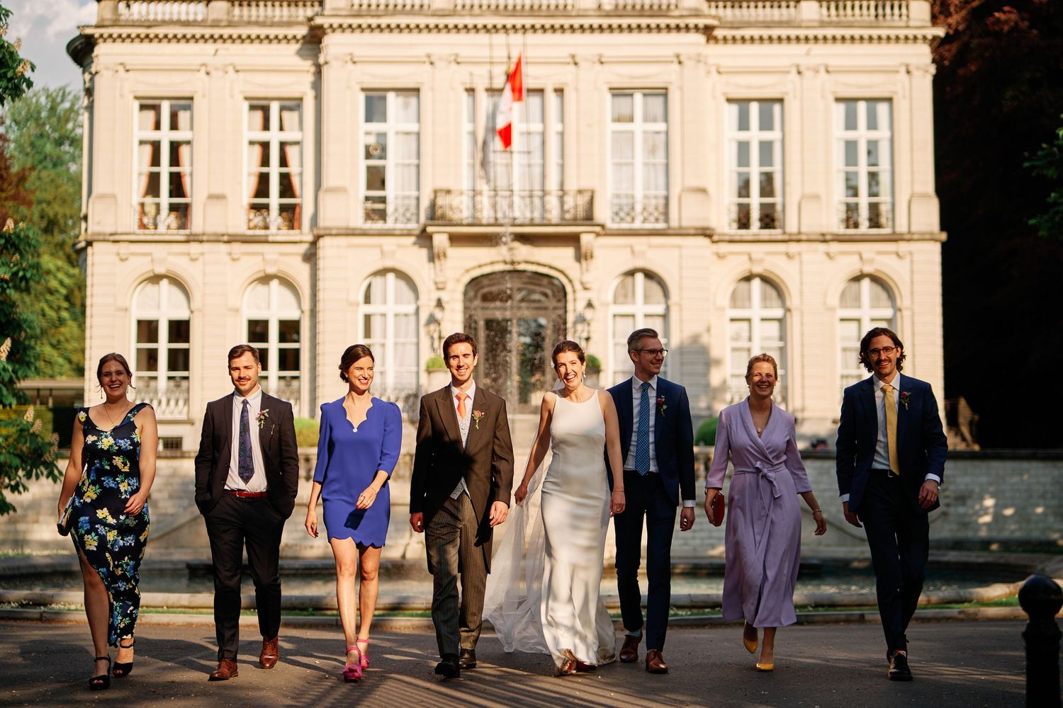 Wedding party walking together in front of an elegant historic building with a Canadian flag.