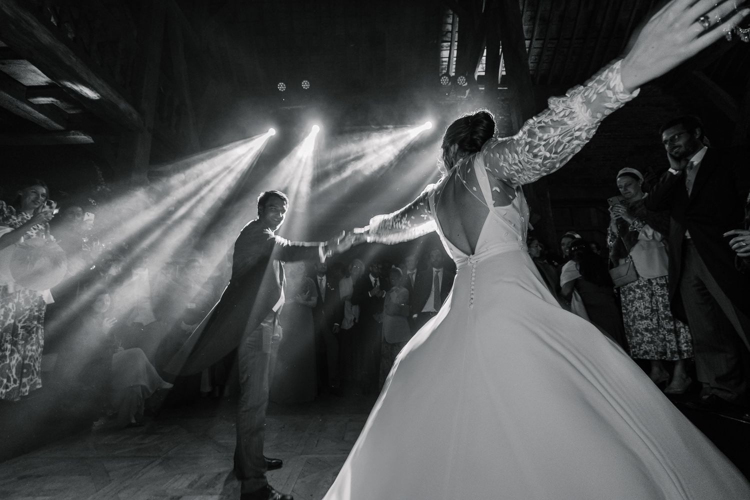 Newlyweds share their first dance under dramatic spotlights at an evening wedding reception.
