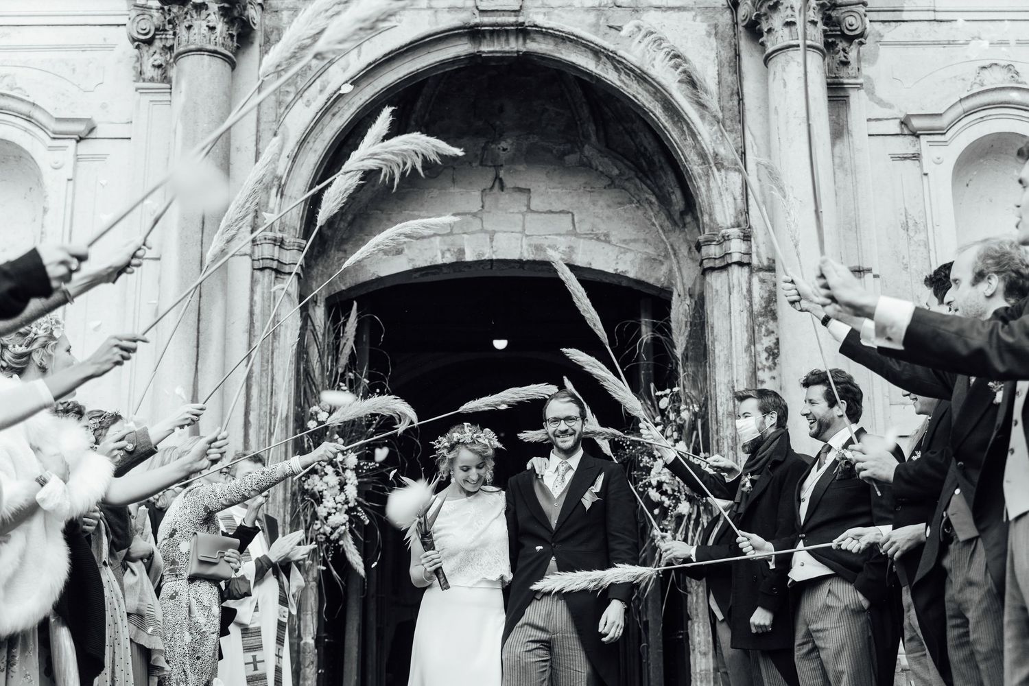 A black and white photograph of a wedding couple exiting a church under raised swords in a military ceremony.