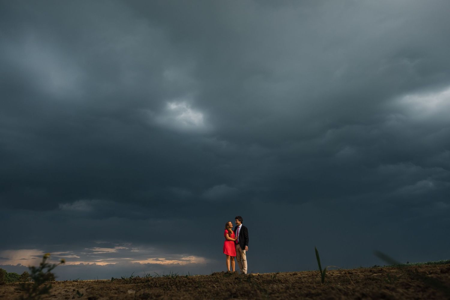 A dramatic stormy sky with dark clouds and a glowing orange horizon creates a moody atmospheric landscape.