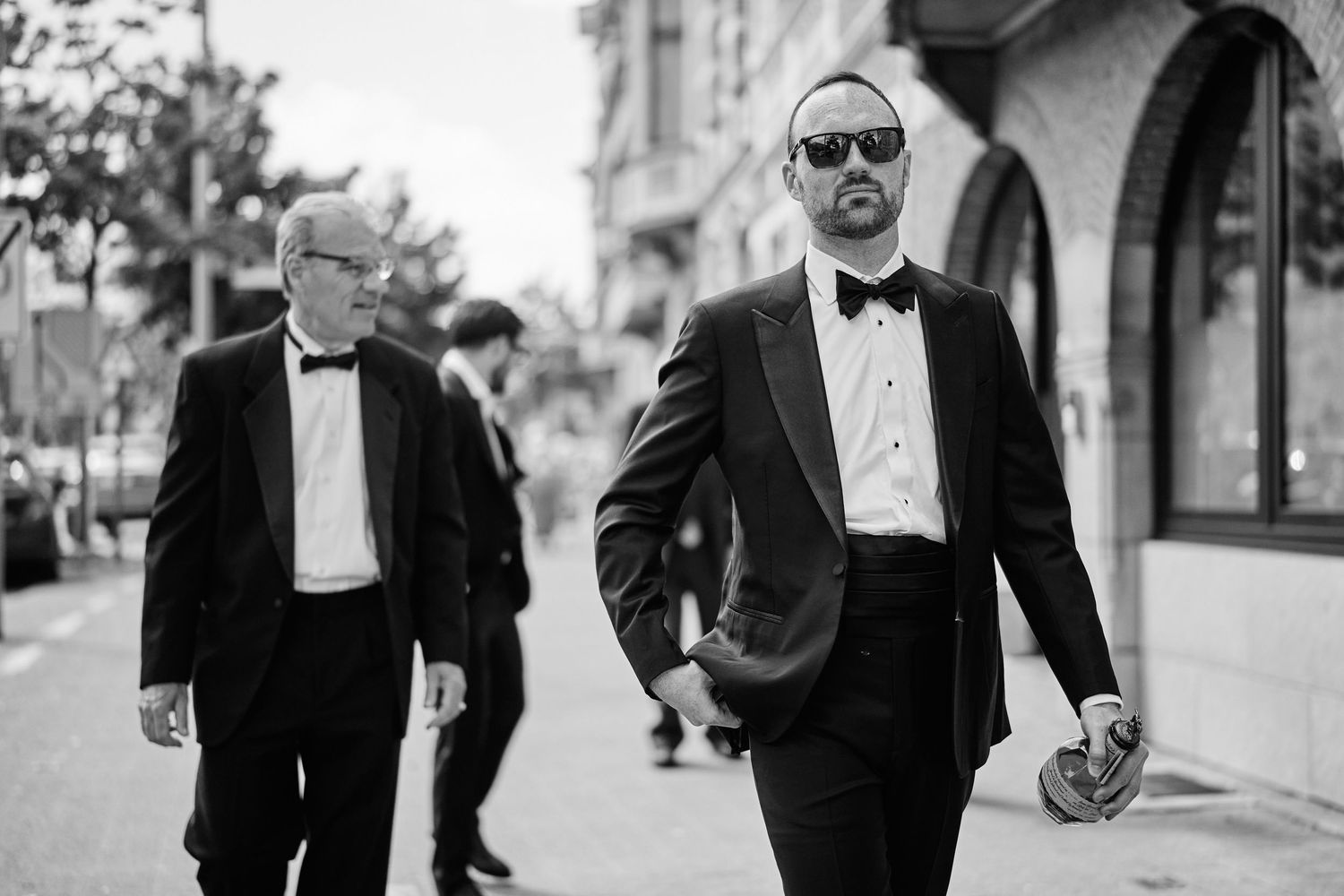 A black and white photo series showing people in formal attire walking and posing outdoors.