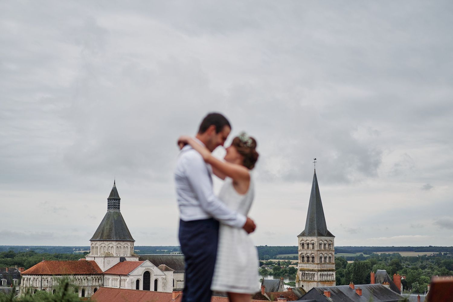 Romantic couple dancing on a rooftop terrace overlooking a historic European city skyline with church spires.