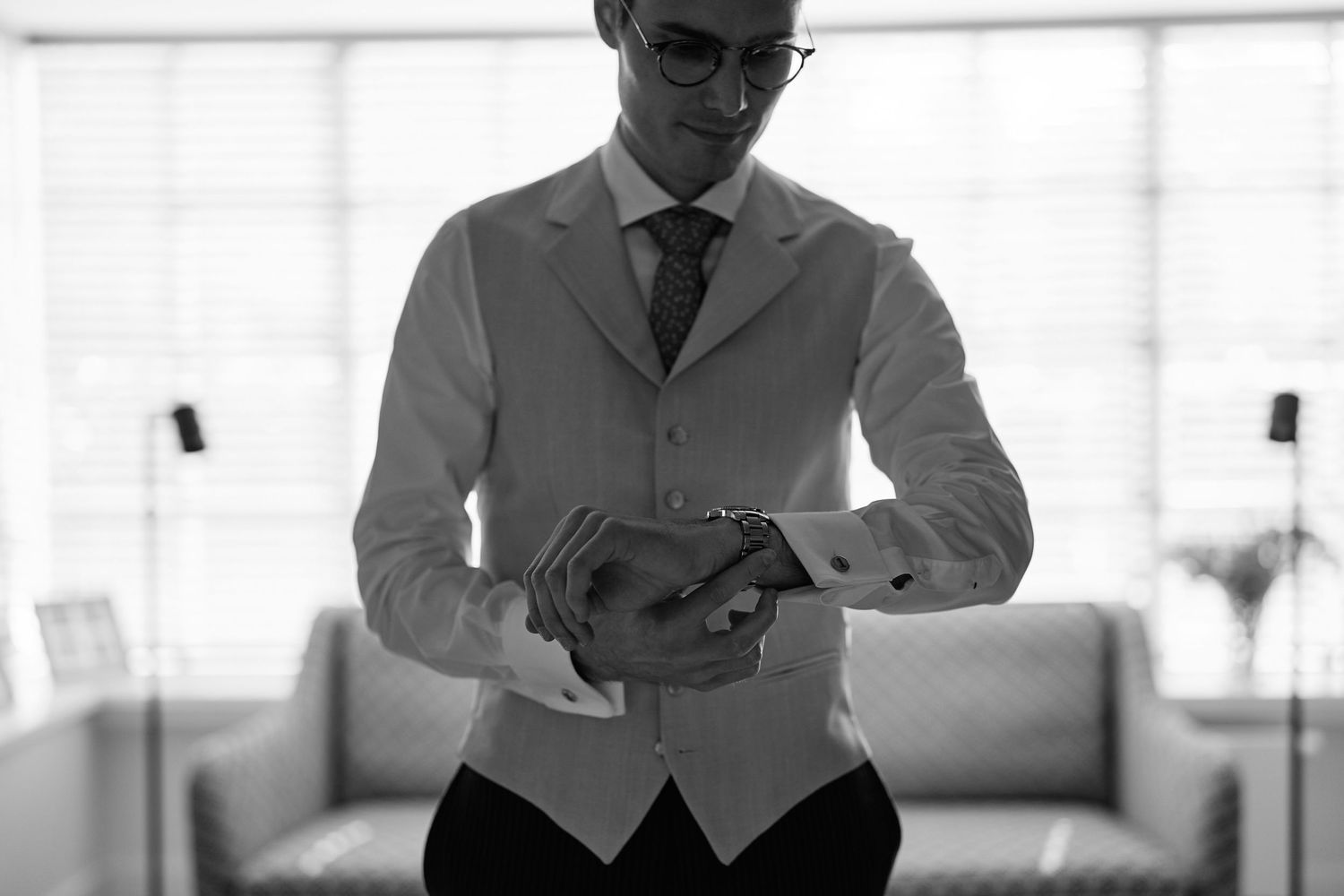 A person in a business suit stands in a modern office setting with white furniture and bright lighting.