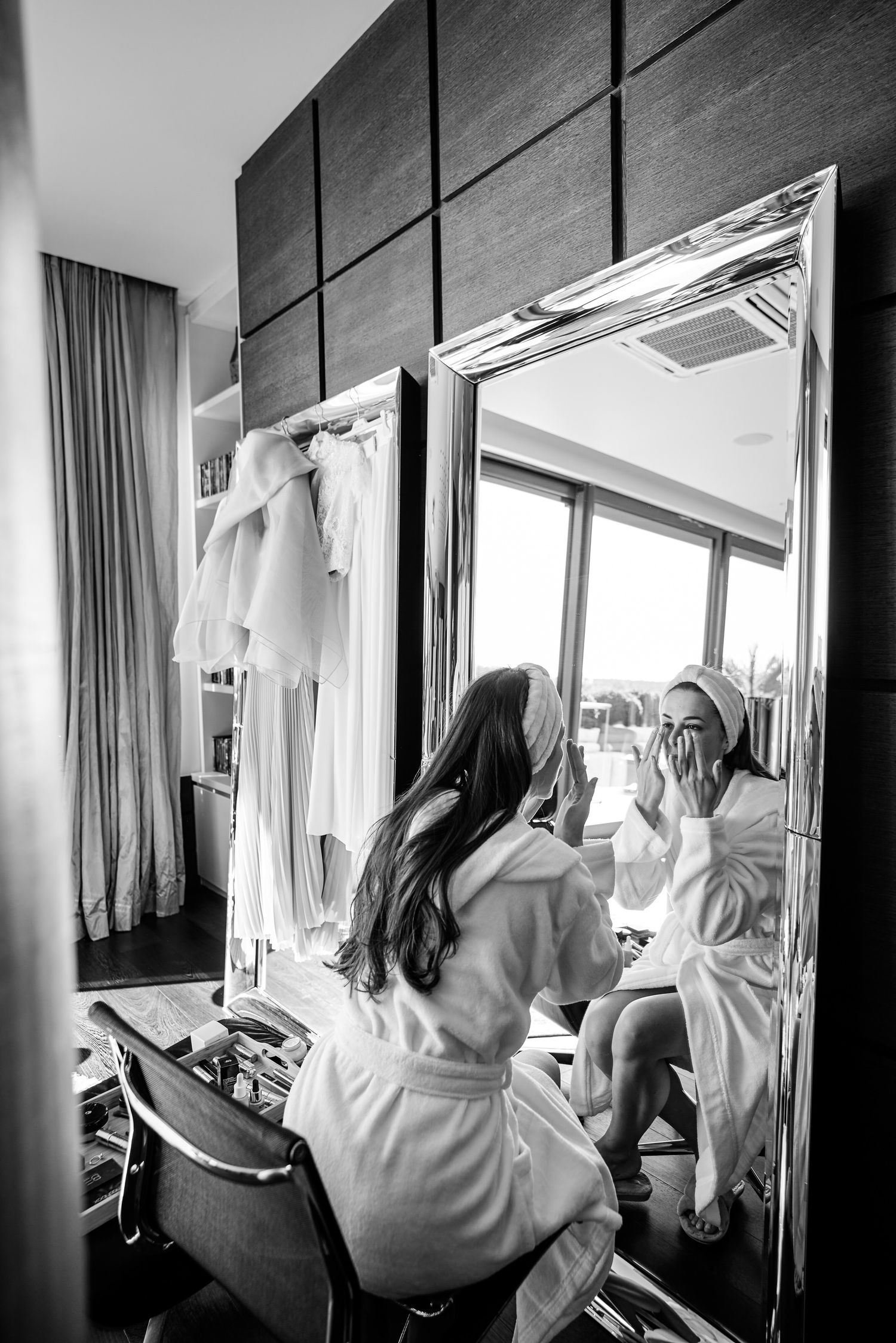 A series of black and white photos showing figures in white robes looking out windows in a hotel room.
