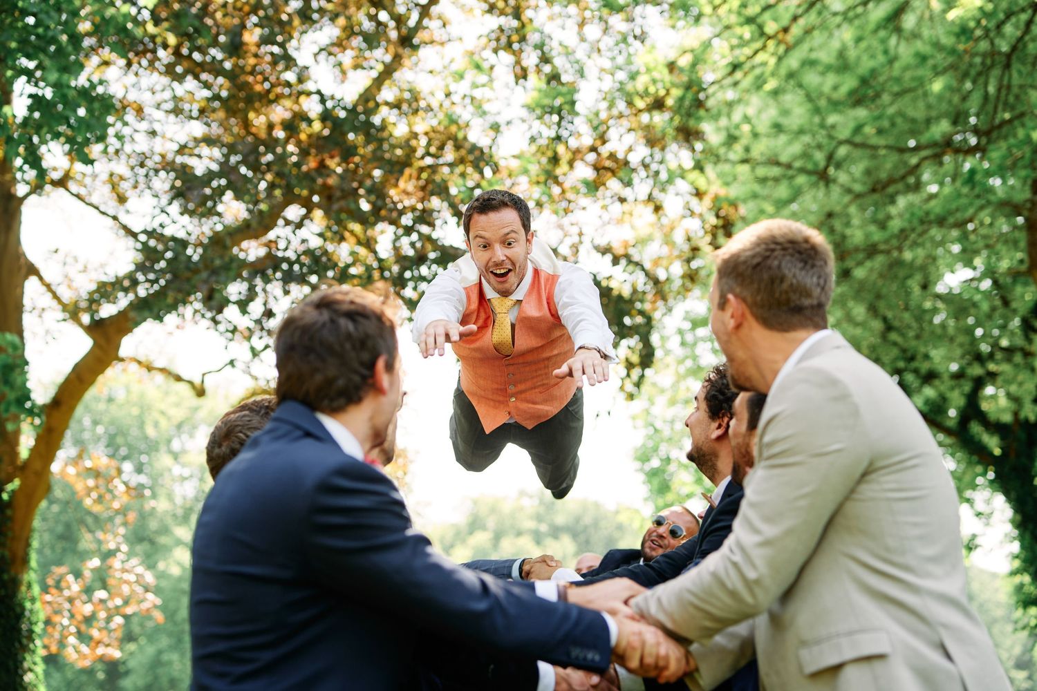 A playful sequence of candid moments captured between wedding guests enjoying themselves outdoors in a garden setting.