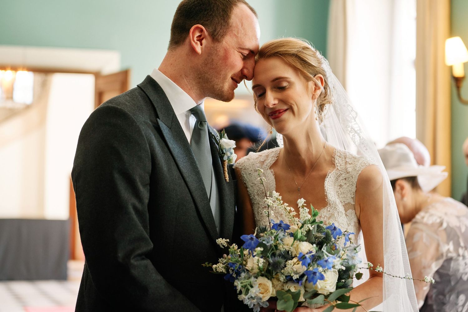A bride and groom share intimate moments during their wedding celebration with blue and white floral bouquet details.