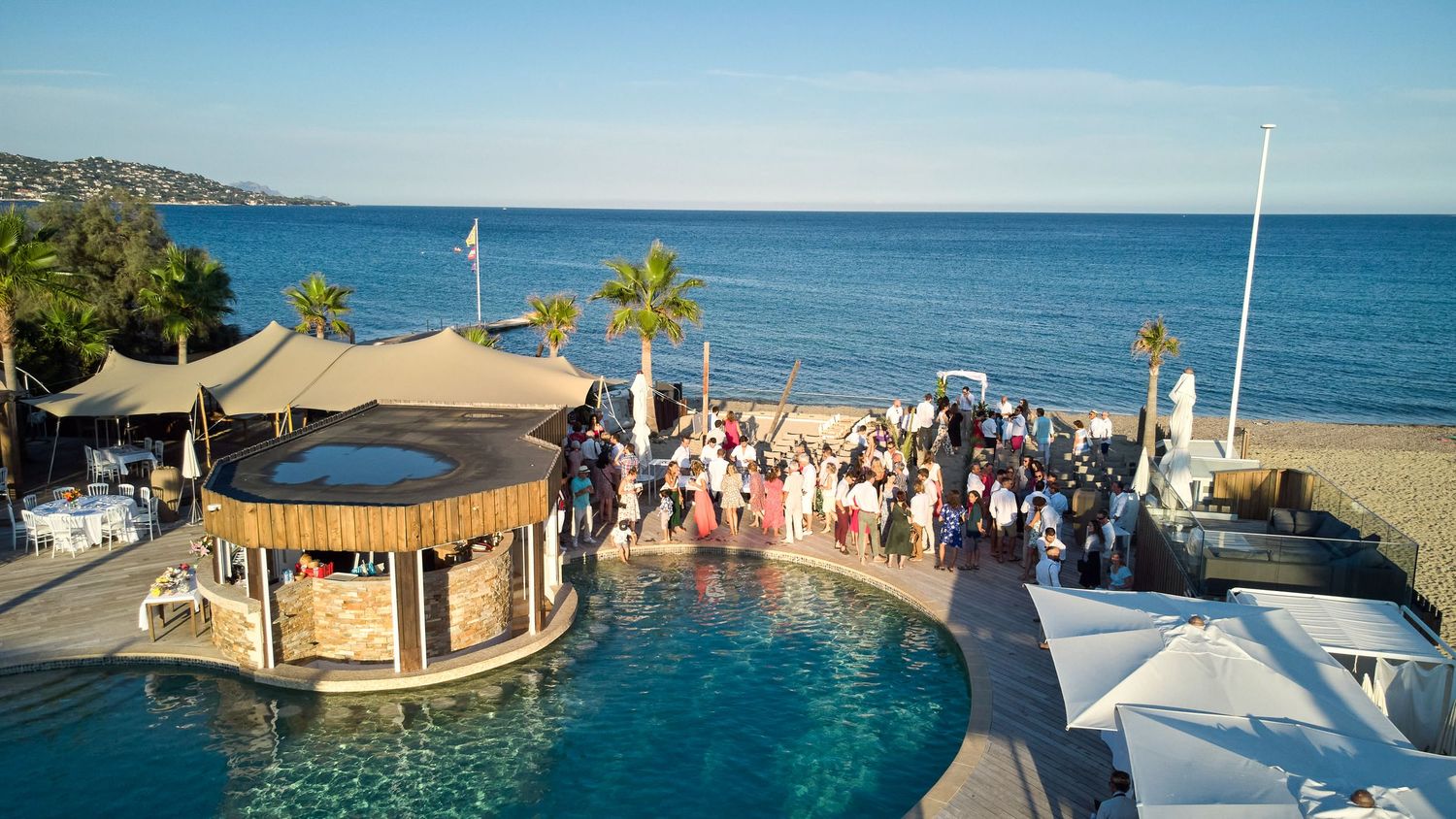 Panoramic view of a luxury beach resort with swimming pools, palm trees, and ocean views along a tropical coastline.