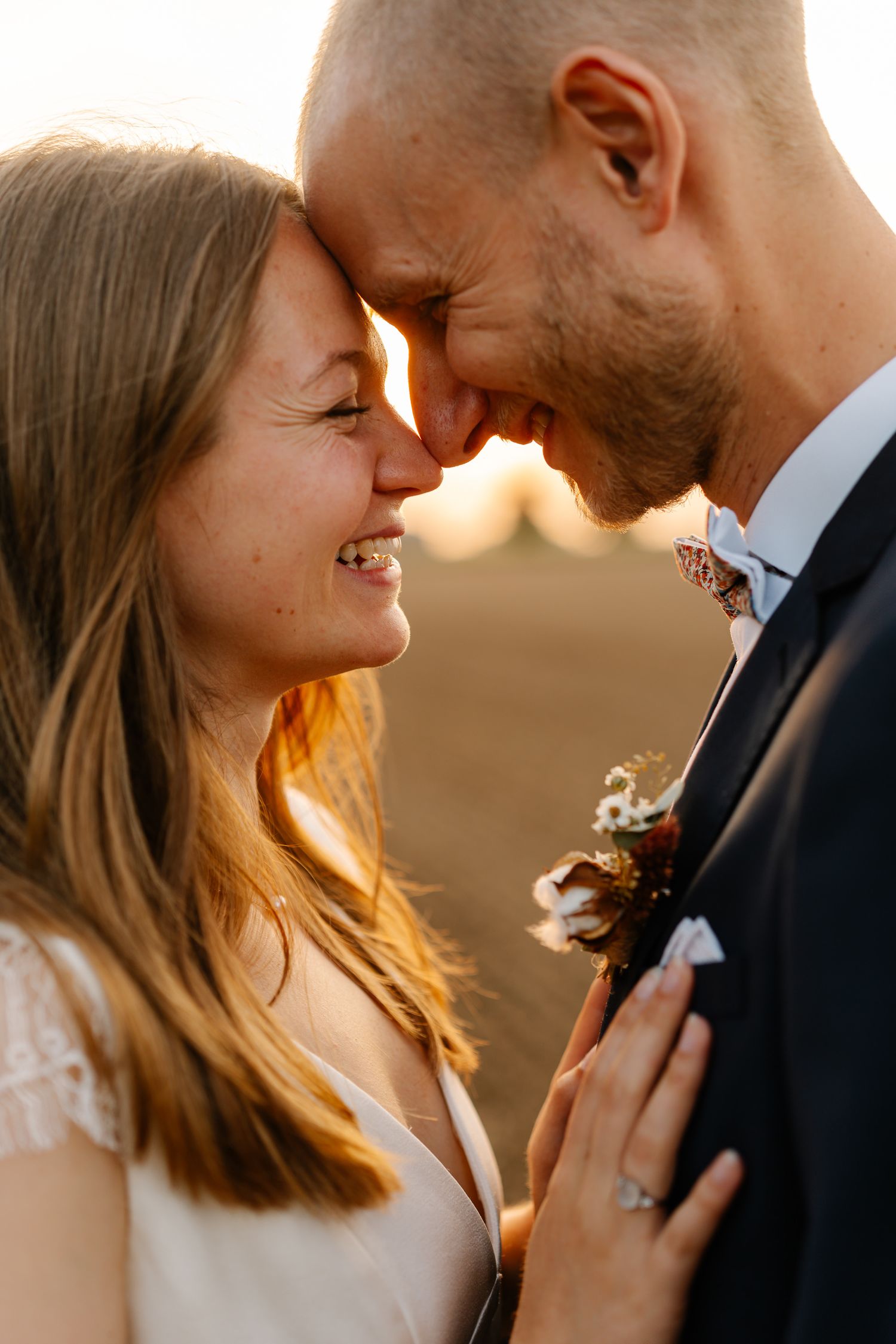A romantic couple embraces in warm sunset light, creating an intimate silhouette against the golden sky.