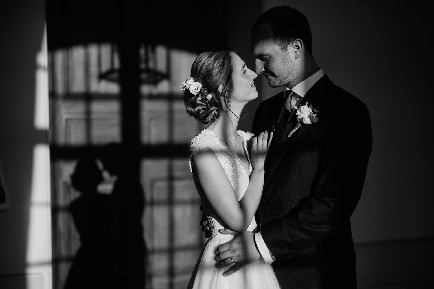 A romantic black and white wedding photo series showing intimate moments between bride and groom in dramatic lighting.