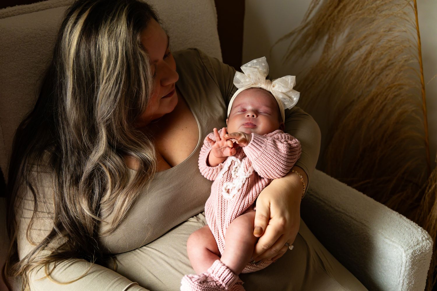 A series of tender moments between parent and newborn baby in soft natural light on a couch.