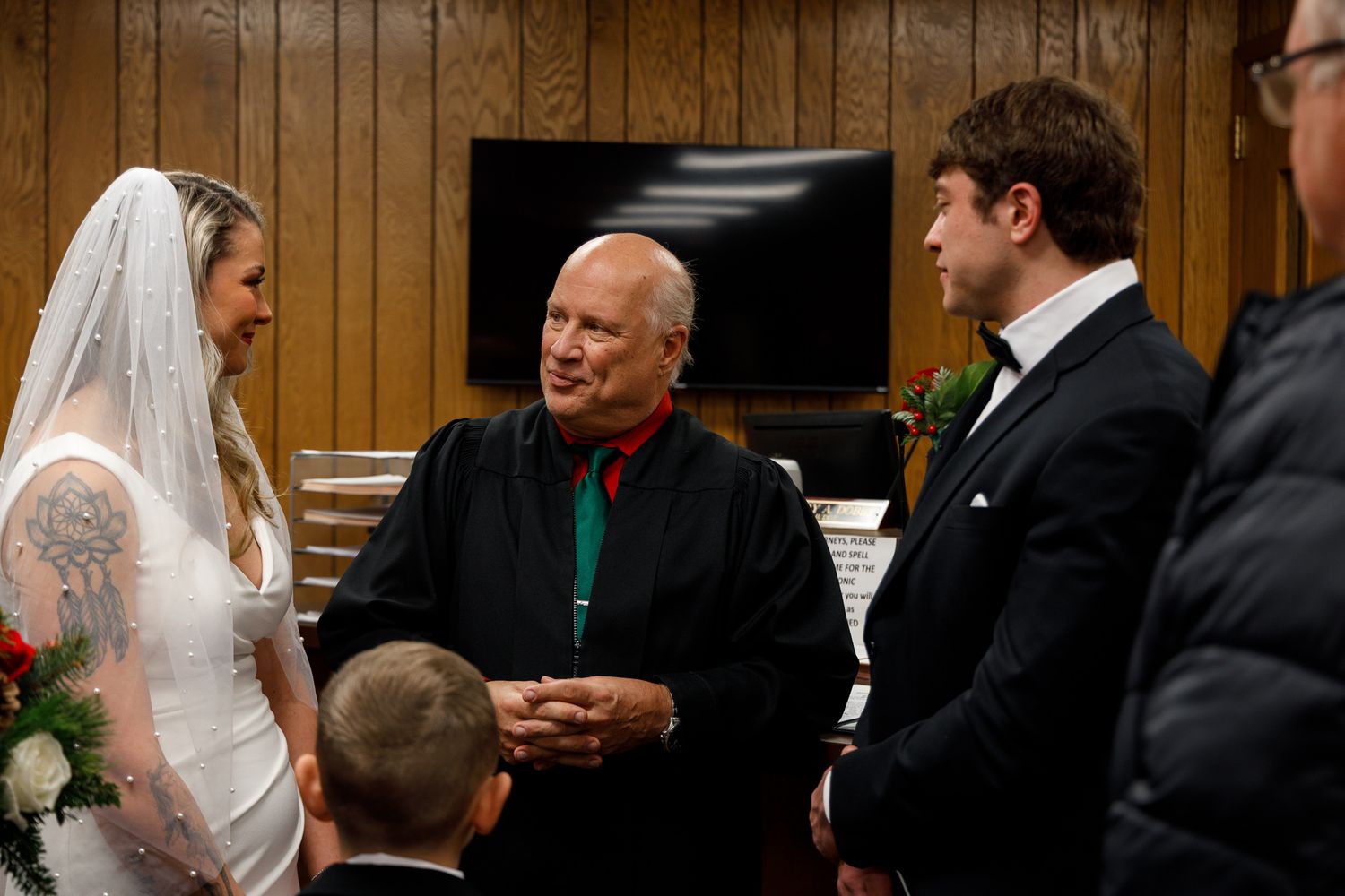 Wedding guests gather in a wood-paneled room during a marriage ceremony.