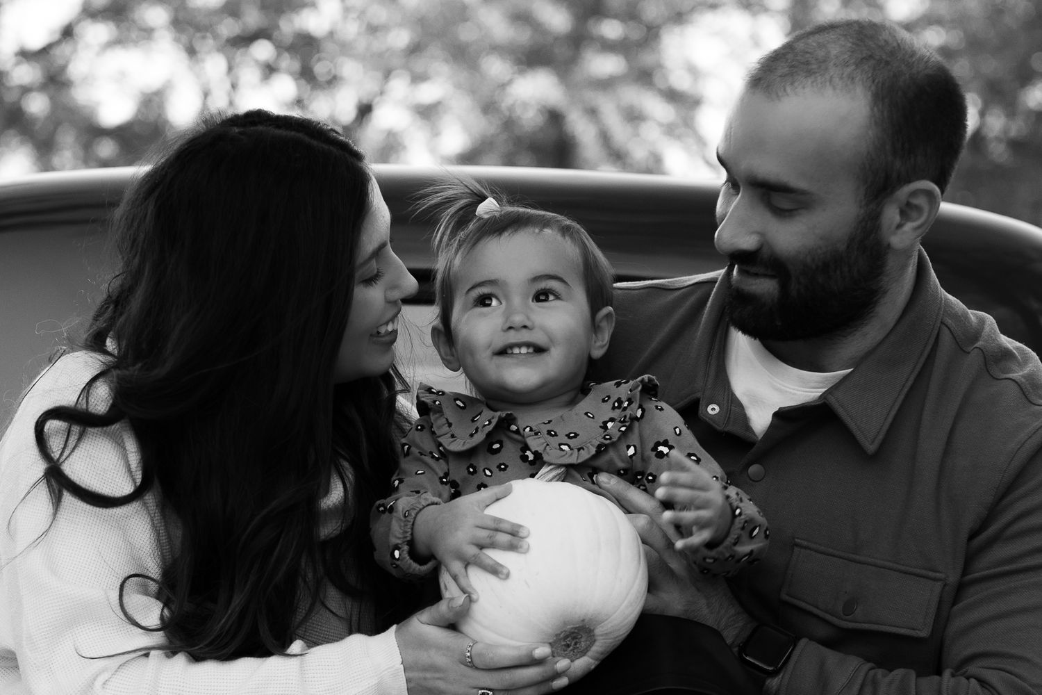 A series of candid black and white photos showing tender family moments between parents and children.