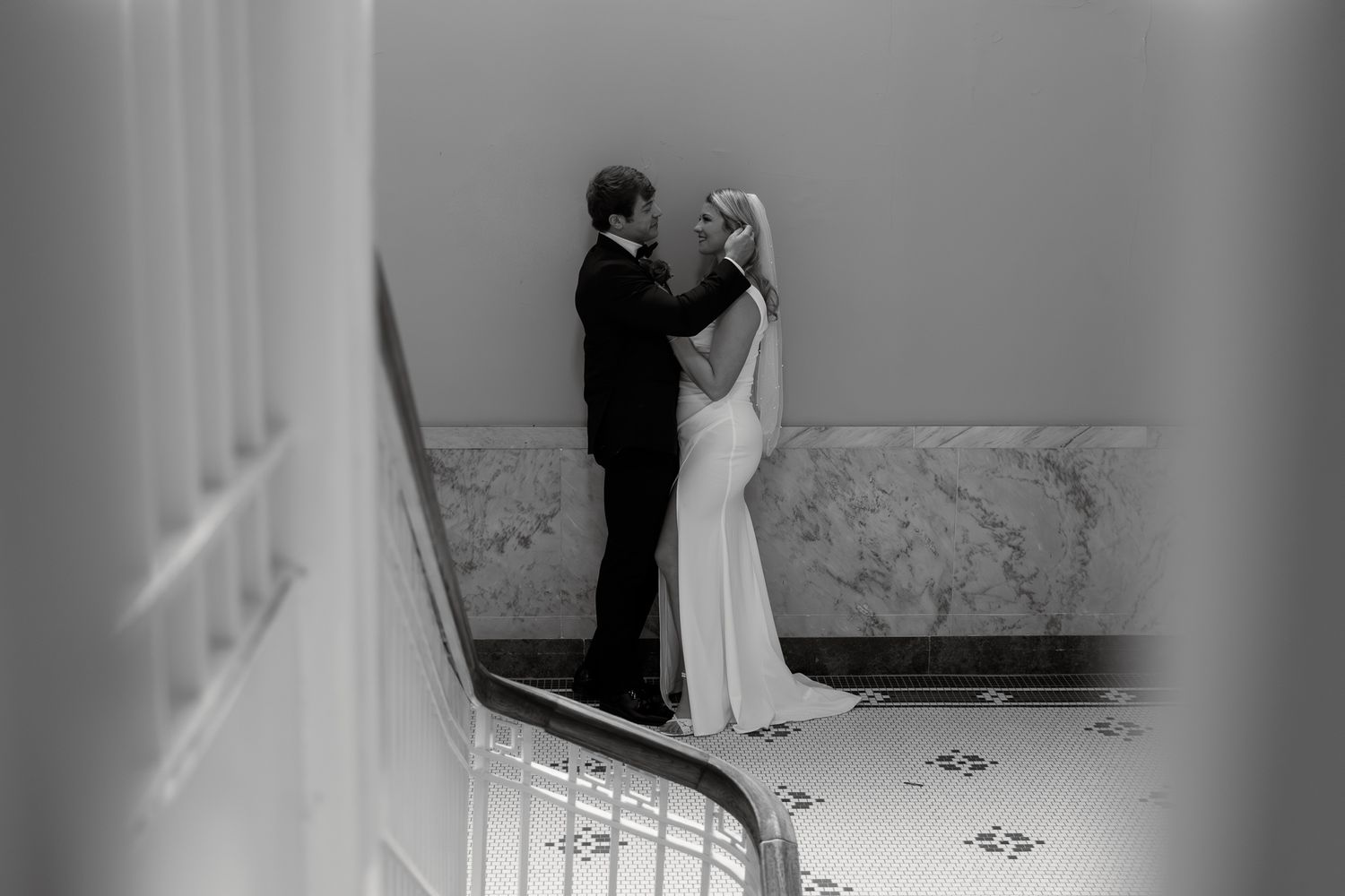 A black and white photo of a couple dancing on elegant marble stairs.