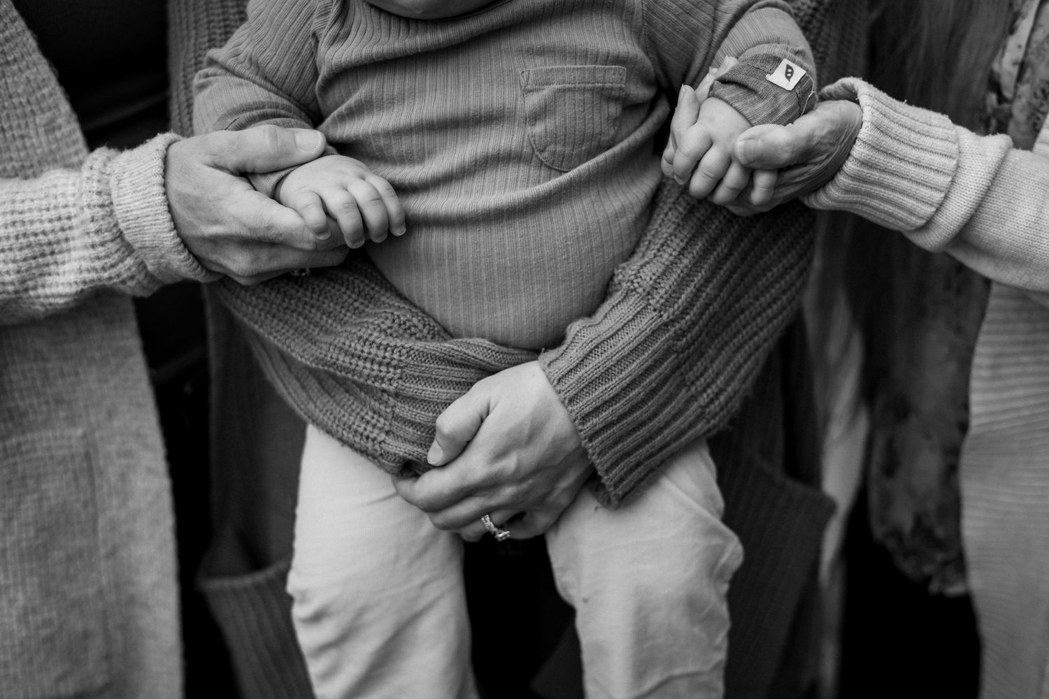 Close-up sequence of hands holding and folding a gray sweater or knit garment.