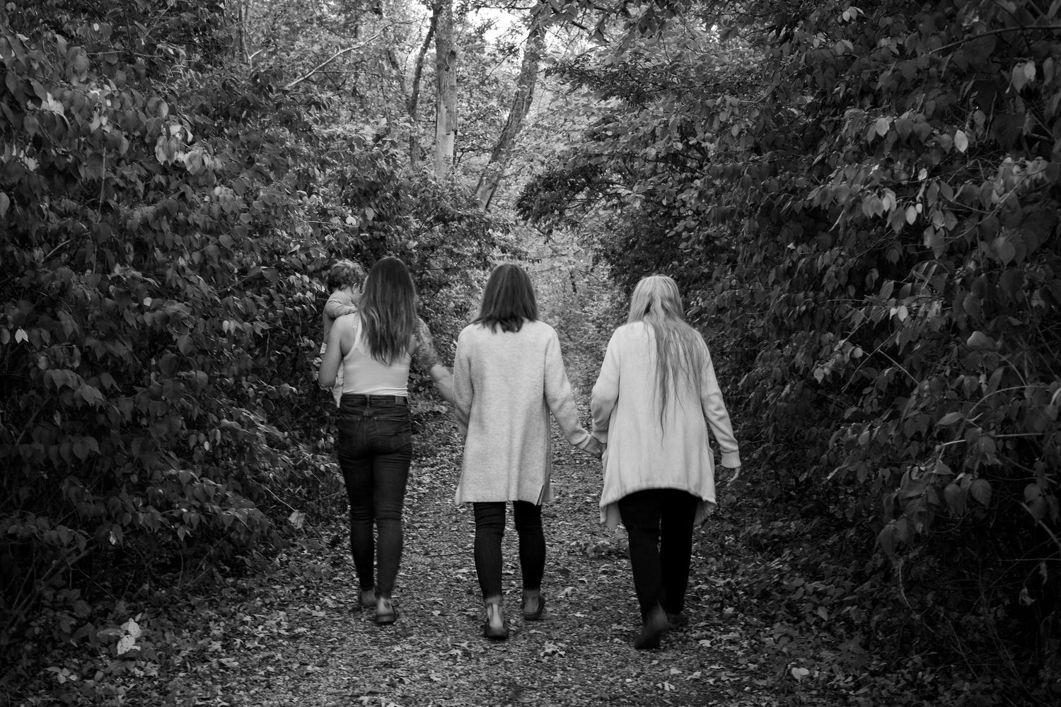 A series of black and white photos showing people walking together on a garden path through lush foliage.